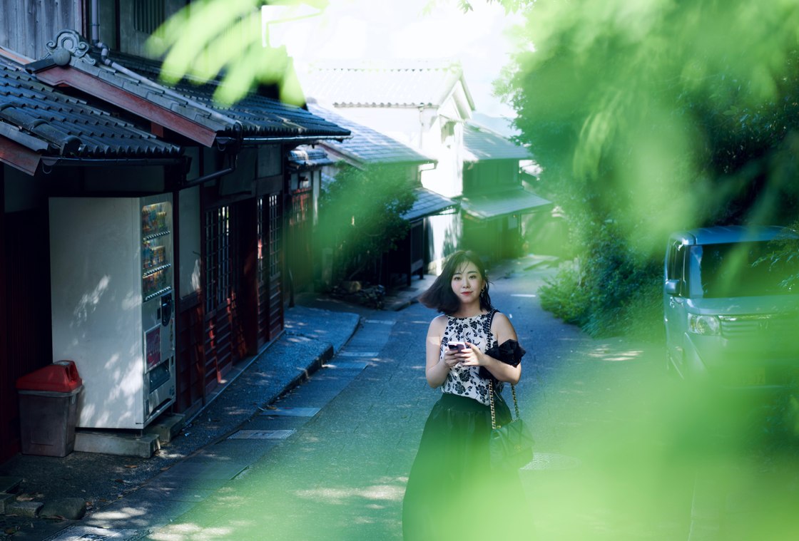 绿叶掩映的街巷里，潞潞拿着手机驻足